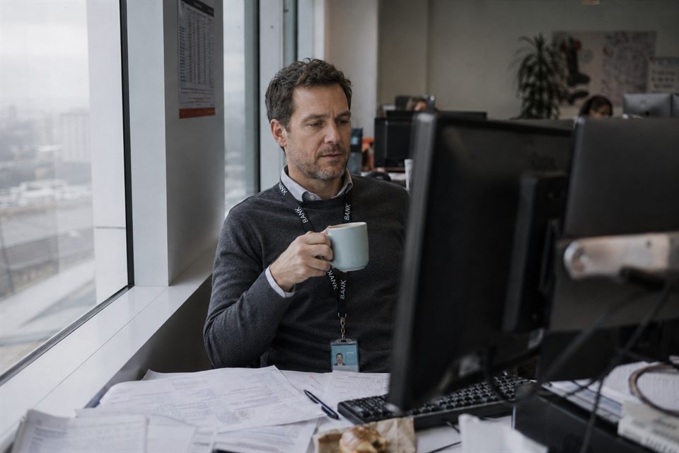 A compliance officer at a bank reviewing trade documents at their desk